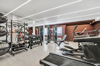A gym with weights and cardio equipment and a window